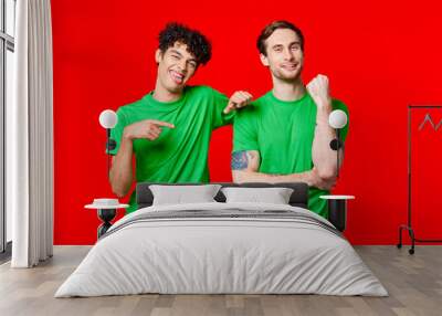 Two cheerful friends in green t-shirts are standing next to each other Wall mural