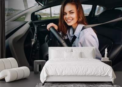 Woman driving car, hands on steering wheel, smiling the image captures a cheerful female driver seated in the vehicle's front seat, portraying confidence and joy behind the wheel Wall mural