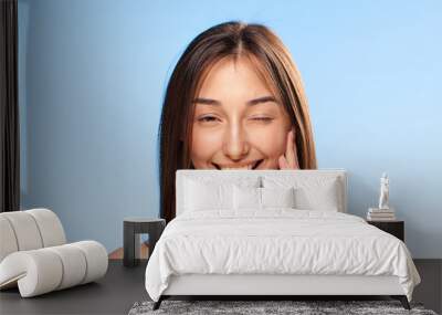 Woman holding a sponge in the teeth on a blue background portrait Wall mural