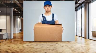 woman in working blue uniform with box in hands delivery service work Wall mural