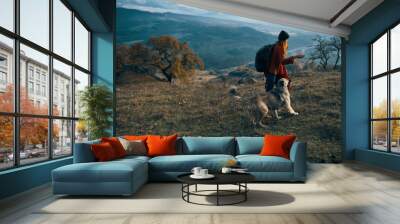 woman with a backpack walks with a dog in the mountains Wall mural