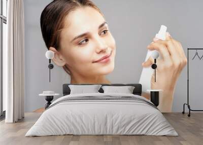 young woman applying cream on her face Wall mural