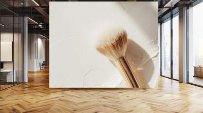 Golden makeup brush creating a shadow on a textured white backdrop, with room for text, ideal for beauty and cosmetics promotion Wall mural