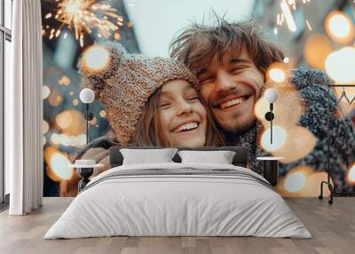 A couple is smiling and hugging in front of a lighted Christmas tree Wall mural