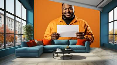 at man holding an blank paper over a orange background, mockup, layout, copy space. Wall mural