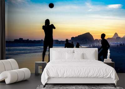 silhouette of jumping man playing beach football on the background of beautiful sunset, atlantic oce Wall mural