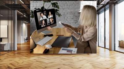 Blond-hair female freelancer having online briefing meeting, discussing new strategy. Stylish business woman learning and discussing financial graphs with colleagues online, distant work concept Wall mural