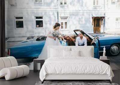 Just married couple in the blue retro car on their wedding Wall mural