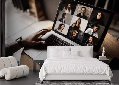 Young African American businessman looks into the laptop screen, speaks by video communication with his colleagues. Business entrepreneur, sitting in an office, pondering a business plan. Wall mural