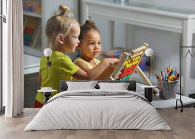 children of different races sit together at the table and count on the abacus Wall mural