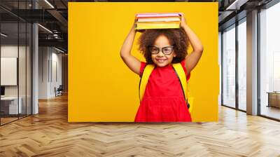 funny smiling Black child school girl with glasses hold books on her head Wall mural