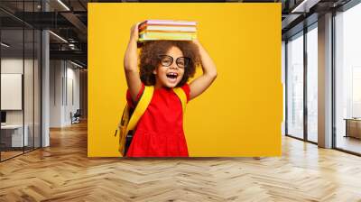 funny smiling Black child school girl with glasses hold books on her head Wall mural