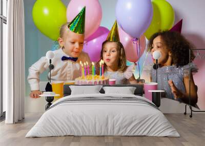 Kids birthday party and children blowing candles on cake together Wall mural