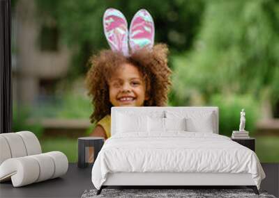 Little Black girl with bunny ears gathering Easter eggs Wall mural