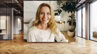 Close up facial portrait of pretty senior woman with freckles and wrinkles smiling at camera widely posing against background of light room with fancy interior, looking elegant and charming Wall mural