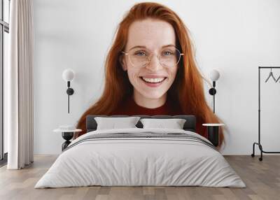 Headshot of cute student girl with loose ginger hair wearing turtleneck and stylish spectacles smiling broadly, having carefree look, laughing from the bottom of her heart. Positive emotions and joy Wall mural