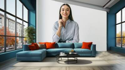 Horizontal portrait of female in jeans and striped shirt with round earrings and smooth long hair posing against white wall with copy space for your advertising content, having bionic prosthetic hand Wall mural