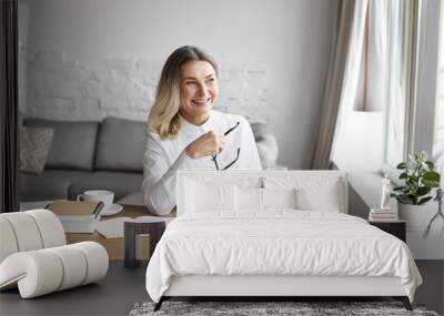 People, age, occupation, profession, hobby, leisure and relaxation. Cheerful middle aged woman smiling broadly, enjoying reading good book during small break while working distantly from home office Wall mural