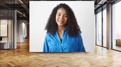 People, lifestyle, ethnicity and fashion concept. Isolated studio shot of gorgeous young African woman with wavy hair and beautiful features expressing positive emotions, posing at white wall Wall mural