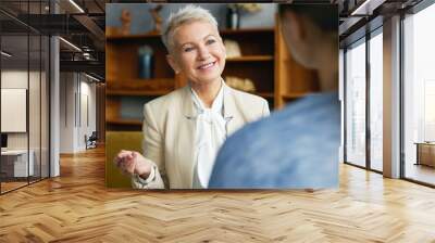 Portrait of experienced stylish human resources woman manager conducting job interview with young female applicant, asking her to tell about work experience, personal qualities and professional skills Wall mural