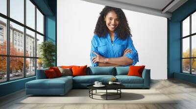 Waist up isolated shot of joyful attractive young African American woman with Afro hairstyle expressing good positive emotions, looking at camera with broad smile, keeping arms folded on her chest Wall mural