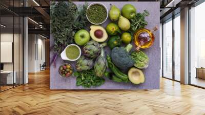 Healthy Green food selection for vegetarians: avocado, apples, broccoli, artichokes, tangerines, mung beans, lettuce, olives, rucola, kale, matcha tea, pears, on gray stone background Wall mural