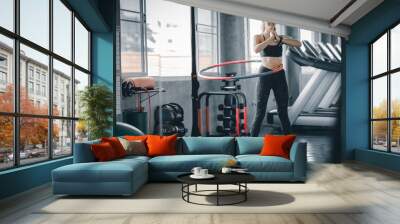 Beautiful caucasian young woman doing hula hoop in step waist hooping forward stance. Young woman doing hula hoop during an exercise class in a gym. Healthy sports lifestyle, Fitness, Healthy concept. Wall mural