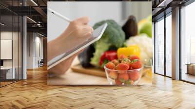 Panoramic of hand professional nutrition healthful surrounded by a variety of fresh fruits and vegetables working on digital tablet. Concept of right nutrition, diet and healthcare. Wall mural