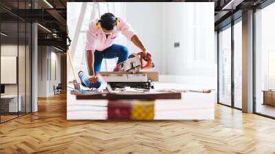 Smart indian contractor hand using sawing machine wood work and working overall equals a wooden bar in the house renovation background. Home improvement ideas concept. Wall mural