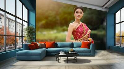 asian women in thai traditional red dress and golden jewellery with flower on hand Wall mural