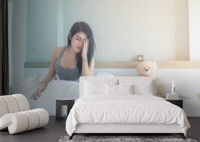 young asian girl sitting holding his head because of stress about insomnia on the white bed in the bedroom Wall mural