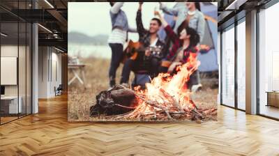 Closeup of bonfire and friendship clinking drinking bottle glass for celebrating in party with mountain meadow and lake view background. People lifestyle and travel vacation. Picnic and camping tent Wall mural