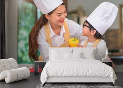 Happy beautiful Asian woman and cute little boy with eyeglasses prepare to cooking in kitchen at home. People lifestyles and Family. Homemade food and ingredients concept. Two Thai looking each other Wall mural