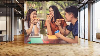 Young Asian people celebrating with pizza in hand. Food and Friendship concept. Lifestyles theme Wall mural