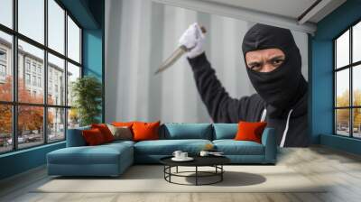 portrait of criminal or bandit wear black mask holding a knife and looking to camera, concept of cutthroat and assassin Wall mural