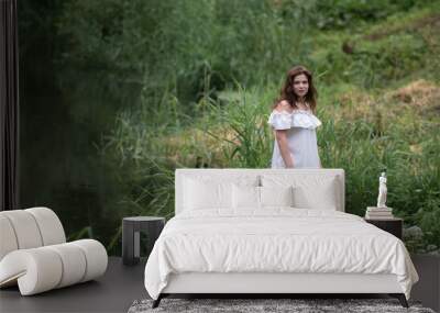 Beautiful young dark-haired girl by the river. Wall mural