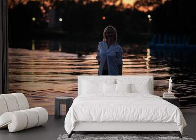 Portrait of a young beautiful blonde girl on the river on a summer evening. Wall mural