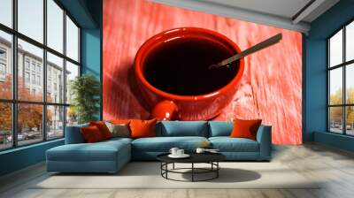 Red Cup with coffee on wooden background. Wall mural