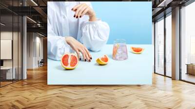 Seductive anonymous woman with well cared hands and manicured nails wearing voluminous sleeves white shirt posing with glass of pink cocktail. Idea of refreshing drink, drink tasting, bar, drink list. Wall mural