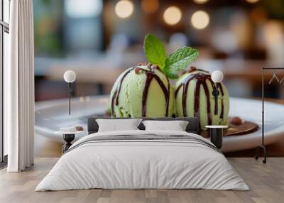 Scoops of green ice cream with chocolate sauce on top and a mint leaf  Wall mural