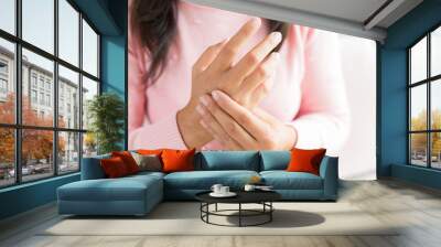 Closeup woman sitting on sofa holds her wrist hand injury, feeling pain. Health care and medical concept. Wall mural