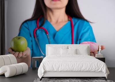 Healthy lifestyle, food and sport concept. Healthy versus unhealthy. Doctor woman hand holding donut and green apple. Wall mural