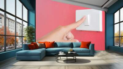 Soft focus woman hand turn on the light with red blackground. Wall mural