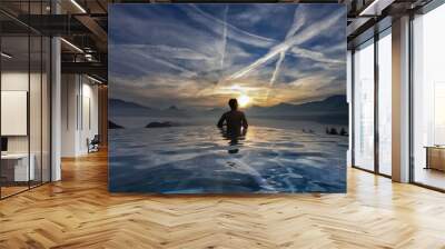 Back of young Asian man without shirt standing in the modern swimming pool admired calm beautiful seascapes surrounded by mountains with amazing cloud appeared as a line in the blue sky during sunset Wall mural