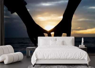 symbols of love. silhouette couple of man and woman hand holding together on sea and sky background  Wall mural