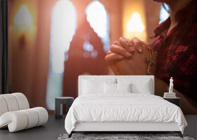 Woman hand holding rosary against cross and praying to God at church. Wall mural