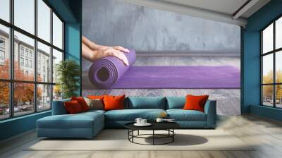 Woman rolling her mat after a yoga class Wall mural