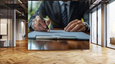 A businessman signing a document in a professional setting. Wall mural