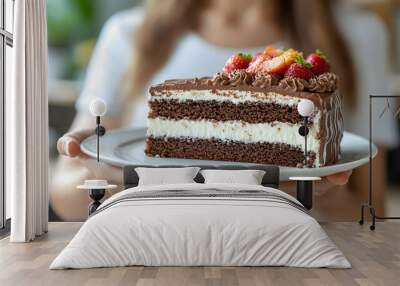 A person holding a slice of chocolate cake with strawberries. Wall mural