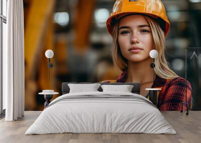 A young woman in a safety helmet and work attire in an industrial setting. Wall mural